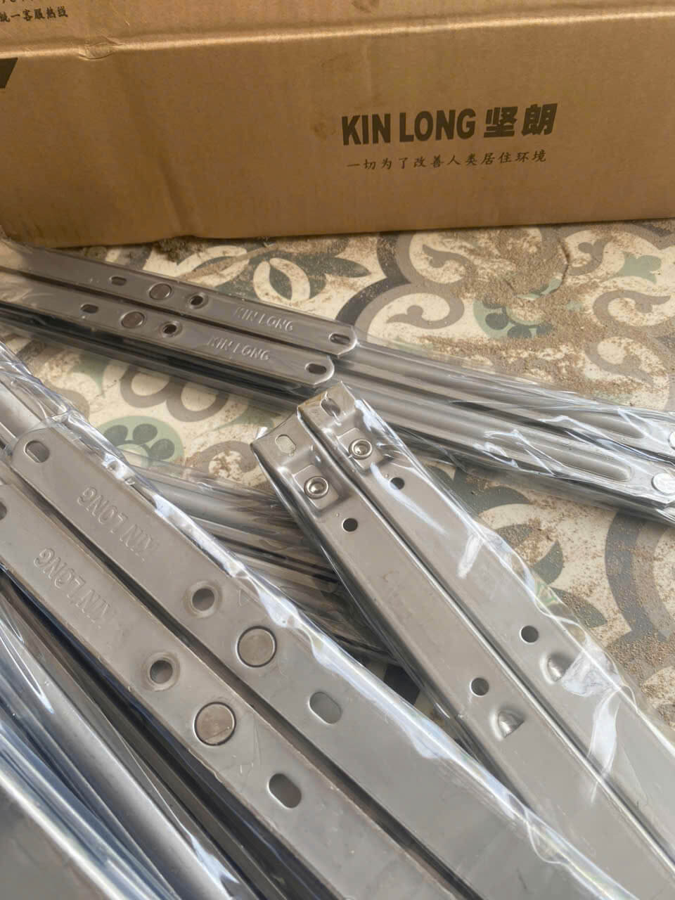 Thanh bản lề inox KIN LONG mới đóng gói đặt trên nền gạch hoa